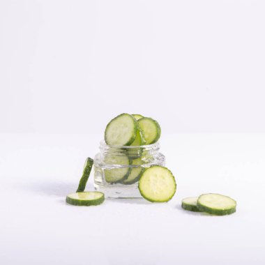 Kozmetik salatalık özü beyaz arka planda cam kabın içinde.