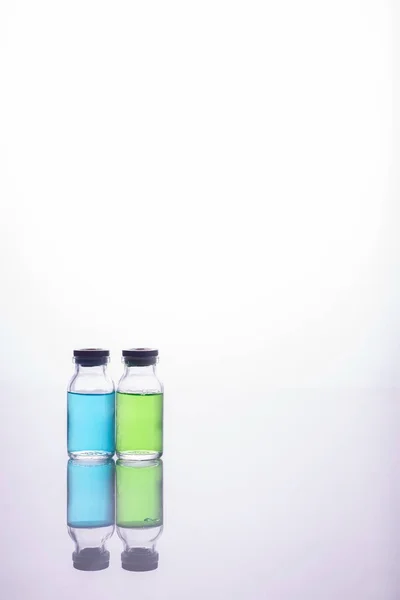 Lékařské láhve s pestrobarevnou kapalinou na bílém pozadí — Stock fotografie
