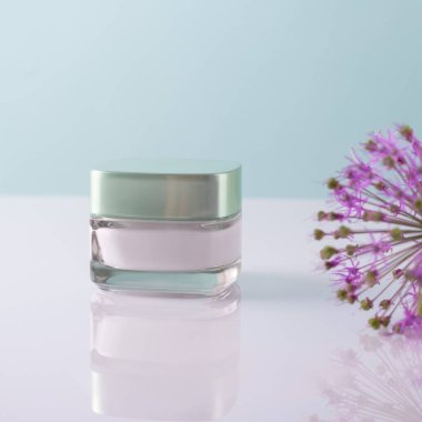 Beyaz bir kabın içinde beyaz-mavi arka planda çiçekler olan güzellik kremi..