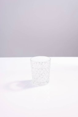 Gri arka plandaki beyaz masada boş kristal cam deney şişesi. minimalizm.