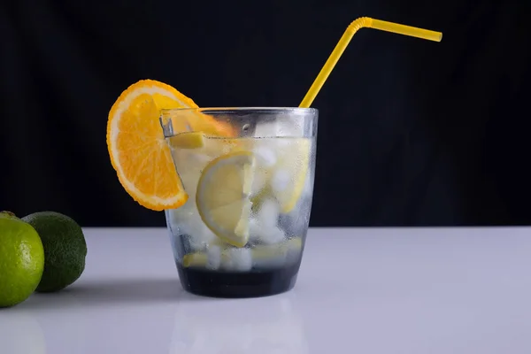 Cóctel de verano en una copa sobre una mesa blanca y fondo negro. concepto minimalista — Foto de Stock