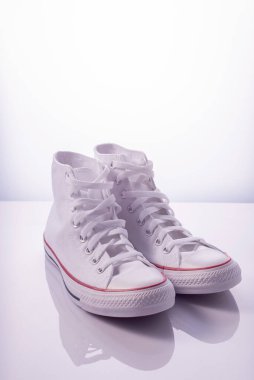 Beyaz arka planda kırmızı çizgili beyaz spor ayakkabılar.