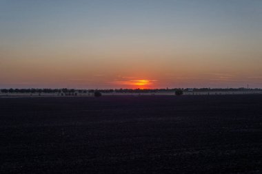 Gökyüzüne karşı batan güneşin kırsal manzarası