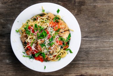 İtalyan tavuk göğsü spagetti kırmızı biber, Parmesan peyniri ve vahşi roket ile yaşıyor. eski ahşap tablo.