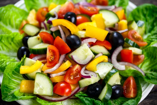 Fräsch nära upp vegetabilisk sallad med svarta oliver, körsbärstomater, gul paprika, rödlök, gurka. — Stockfoto