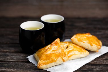 Eski ahşap masa üzerinde sığır eti, patates ve soğan ve yeşil çay bardağı ile ev yapımı pasta