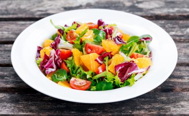 Ahşap masa üzerinde taze turuncu, sebze salatası.