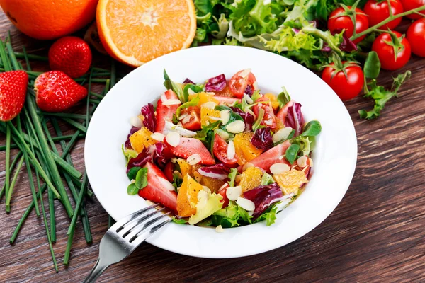 Laranja fresca, salada de legumes de morango. na mesa de madeira . — Fotografia de Stock