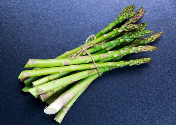 Färska knippa sparris på blå tabellbakgrund — Stockfoto