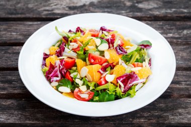 Ahşap masa üzerinde taze turuncu, sebze salatası.