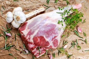Raw lamb leg on crumpled paper background with herbs. clipart
