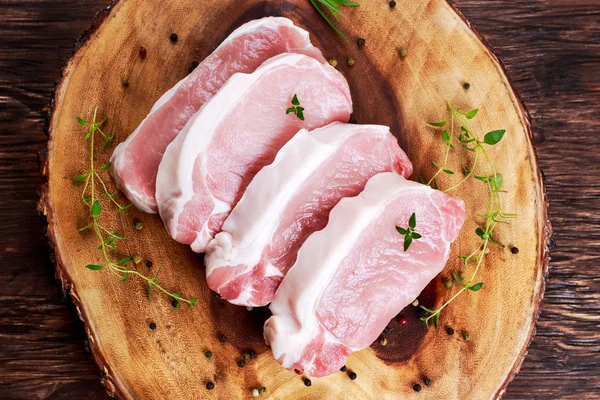 Chuletas de cerdo sin hueso frescas crudas con hierbas. sobre tabla de madera . —  Fotos de Stock