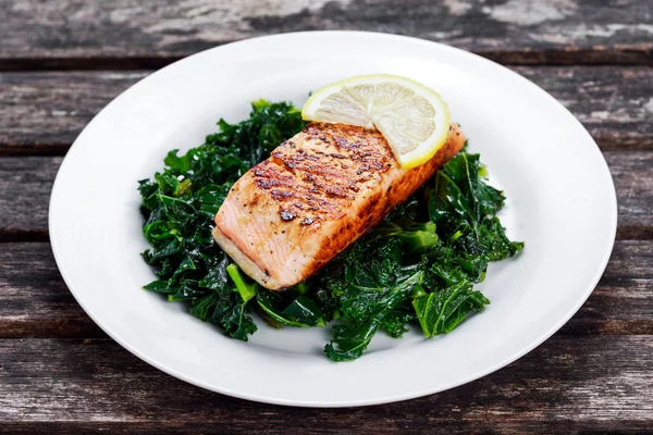 Gebratener Lachs mit Grünkohl auf Teller — Stockfoto