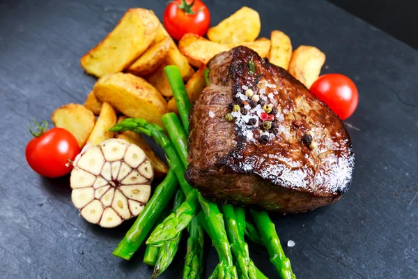 Steak de boeuf Mignon cuit aux asperges, pommes de terre, ail et tomates . — Photo