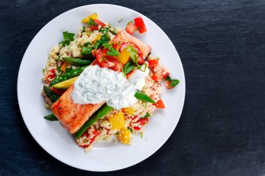 Pan kızarmış somon kabak ihale kuşkonmaz ile hizmet üzerinde tatlı domates, sarı biber, eski mavi taş zemin üzerine dereotu ile Yunan yoğurt ile karışık kuskus