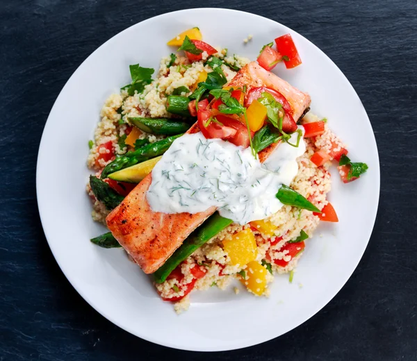 Pan fried Salmon with tender asparagus, courgette served on couscous mixed with sweet tomato, yellow pepper, greek yogurt with Dill on old blue stone background — Stock Photo, Image