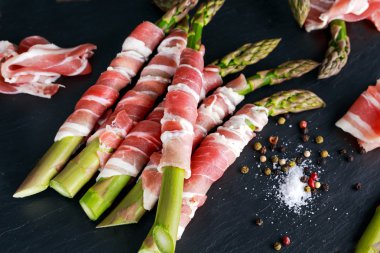 Taze organik çiğ jambon sarılı kuşkonmaz taş zemin üzerine