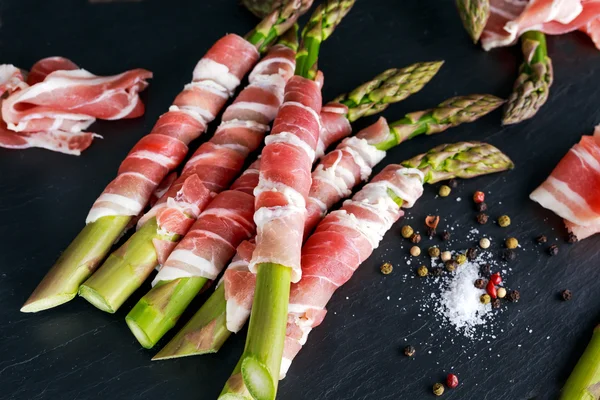 Taze organik çiğ jambon sarılı kuşkonmaz taş zemin üzerine