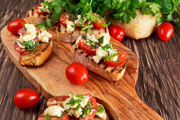 Grilled appetizer bruschettas with tomatoes, mozzarella and parsley sprinkle — Stock Photo, Image