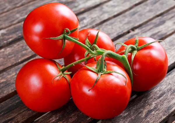 Organiczne winorośli dojrzałe pomidory na drewnianym stole — Zdjęcie stockowe