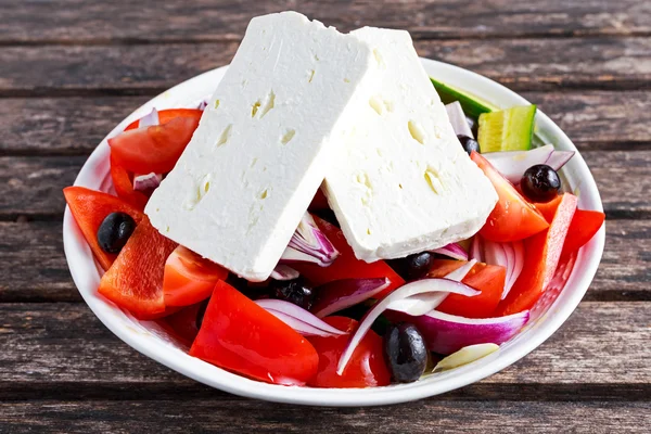 Ensalada griega con pimiento dulce fresco, cebolla roja, pepino, aceitunas negras y queso feta rociado aceite de oliva virgen extra sobre mesa de madera —  Fotos de Stock