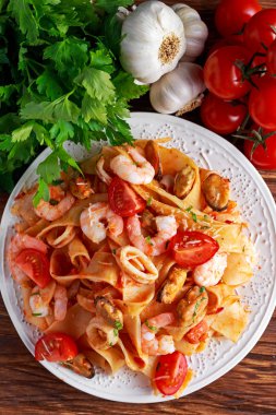 Karides, kalamar, midye, domates ve otlar ile lezzetli Pappardelle makarna.