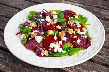 Taze tatlı bebek ıspanak, lahana marul, fındık, ahşap masa üzerinde beyaz peynir ile sağlıklı pancar salatası.