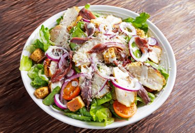 Ceasar salata ızgara tavuk fileto, kırmızı soğan, marul, portakal kiraz domates, kruton, rendelenmiş parmesan peyniri, tecrübeli hamsi ile