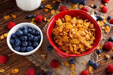 Mısır gevreği böğürtlen ahududu, yaban mersini, bardak süt ve tatlı bal ile.