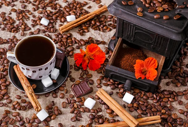 Tasse Kaffee wird auf alte Eisenmühle mit Schokolade, Zucker, Zimtbohnen getan — Stockfoto