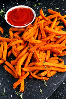 Sağlıklı ev yapımı pişmiş turuncu tatlı patates kızartması ketçap, otlar, tuz ve biber ile.