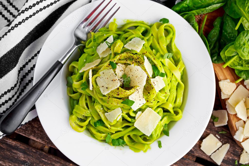 Tagliatelle pasta with spinach, avocado and parmigiano cheese, herbs in white plate. concept of healthy food