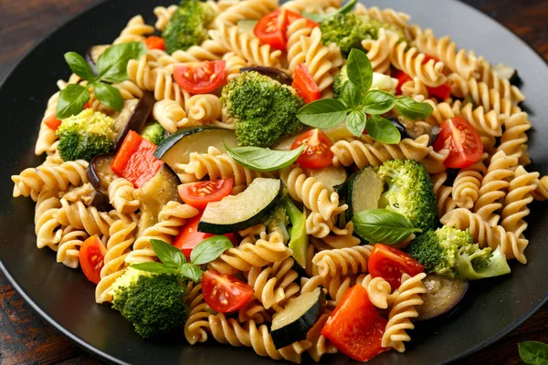 Massa Fusilli com legumes, brócolis, abobrinha, pimenta vermelha, berinjela, tomate e manjericão em placa preta — Fotografia de Stock