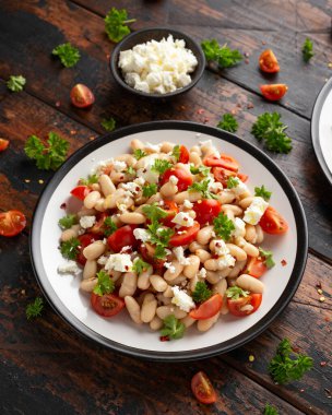 Kiraz domatesli beyaz fasulye salatası, Feta peyniri ve maydanoz. Sağlıklı vejetaryen yemeği.