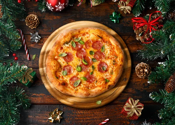 Boże Narodzenie Salami, Pepperoni Pizza z dekoracji, prezenty, zielona gałąź drzewa na drewnianym rustykalnym stole. — Zdjęcie stockowe