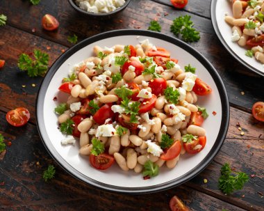 Kiraz domatesli beyaz fasulye salatası, Feta peyniri ve maydanoz. Sağlıklı vejetaryen yemeği.