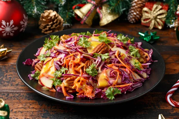 Noël Chou rouge, carottes, pommes et noix de pécan Salade avec décoration, cadeaux, branche d'arbre vert sur table rustique en bois — Photo