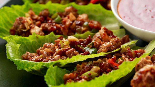 Chilli Beef Lettuce Wraps with sauce on black plate