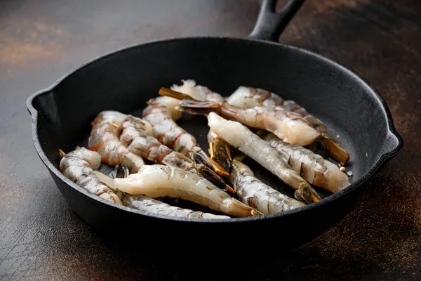 Tiger prawns skewers in iron cast pan, ready to cook.