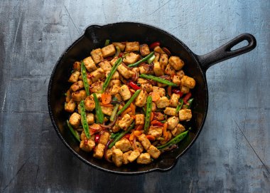 Vejetaryen eti ücretsiz micoprotein parçaları sebze kızartması dökme demir tavada servis edilir.