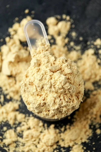 Scoop of Pea Vegan protein powder on dark rustic background. Sport nutrition.