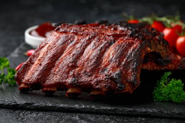 Izgara domuz pirzolası, bol soslu ve taş tahtada otlar.