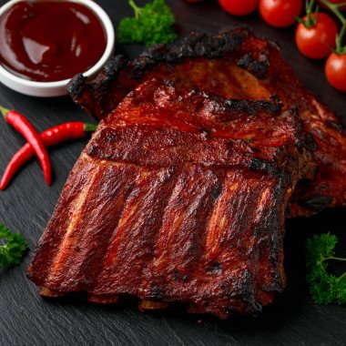 Izgara domuz pirzolası, bol soslu ve taş tahtada otlar.