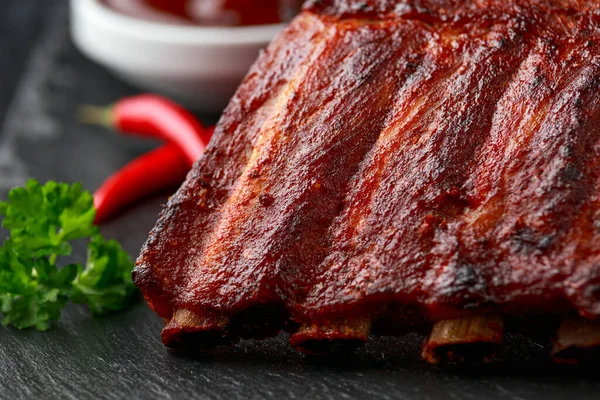 Gegrilde varkensribbetjes met bbq saus en kruiden op stenen plank — Stockfoto