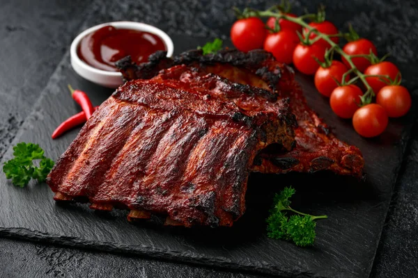 Gegrilde varkensribbetjes met bbq saus en kruiden op stenen plank — Stockfoto