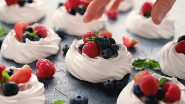 Womans Hand recoger merengue nido mini pavlova pastel con bayas frescas fresa arándano frambuesa y menta para el desierto saludable — Vídeos de Stock