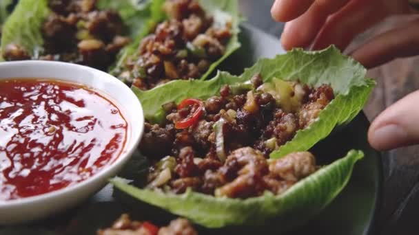 Woman take Chilli Beef Lettuce Wraps from black plate — Stock Video