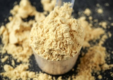 Koyu kırsal arka planda bir kepçe Pea Vegan protein tozu. Spor beslenmesi.