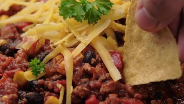 Picking Chilli con Carne with tortilla chips. Mexican food. — Stock Video