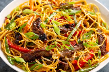 Kızarmış erişteyi sığır eti ve sebzeyle karıştırın. Asya usulü yemek.